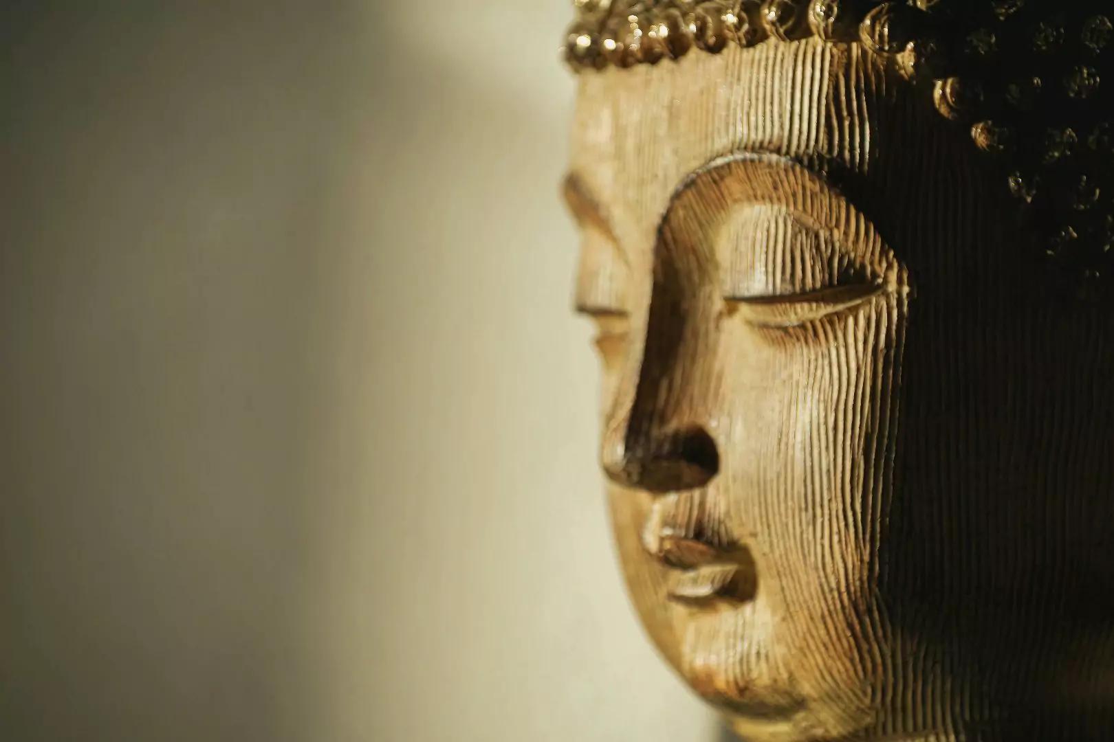 Close up of a wooden Buddha statue face with yellow background.